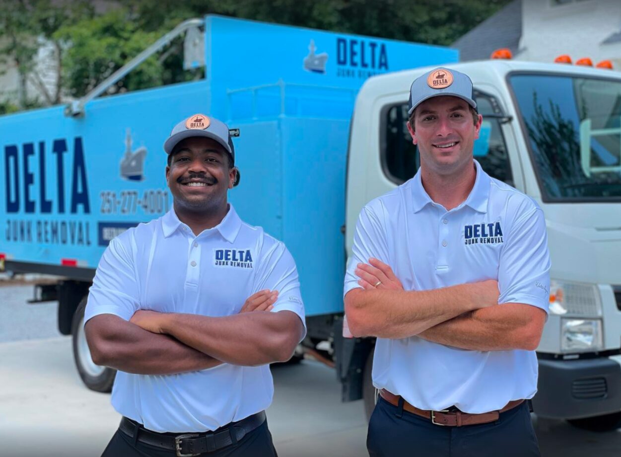 Delta Junk Removal owners standing in front of their dump trucks on the Gulf Coast, Alabama